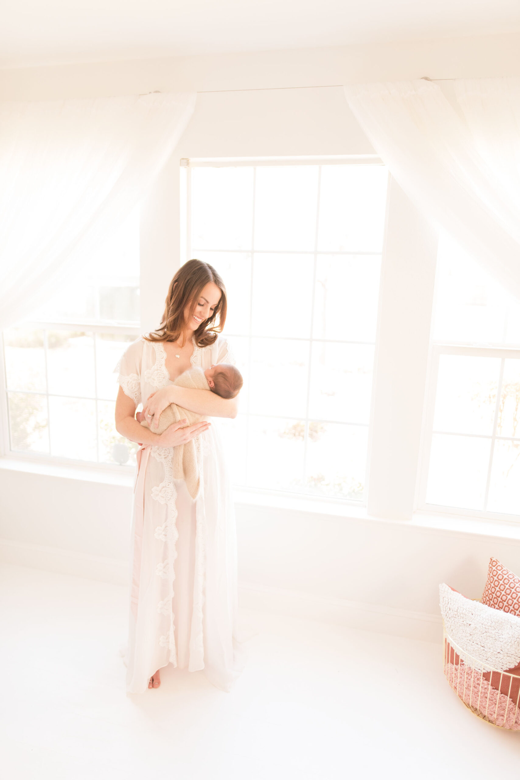 A new mother stands by a window with her baby | Sacramento Newborn And Family Photographer 