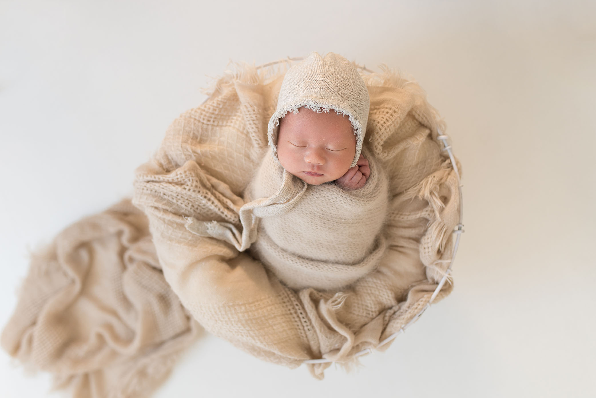 During a Sacramento Newborn Photography shoot, a baby sleeps in a basket. 