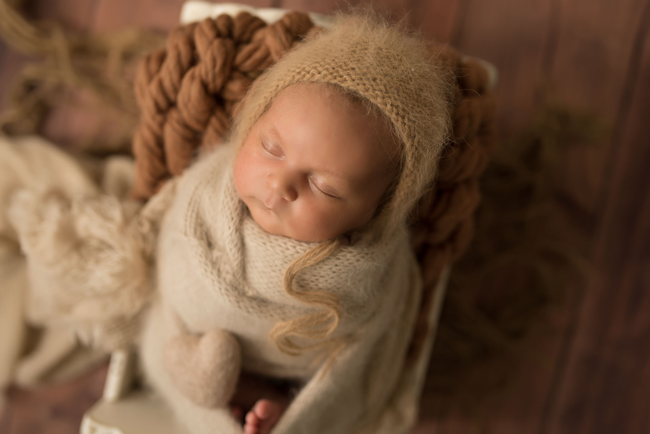 A newborn naps peacefully while wrapped in a soft blanket. 