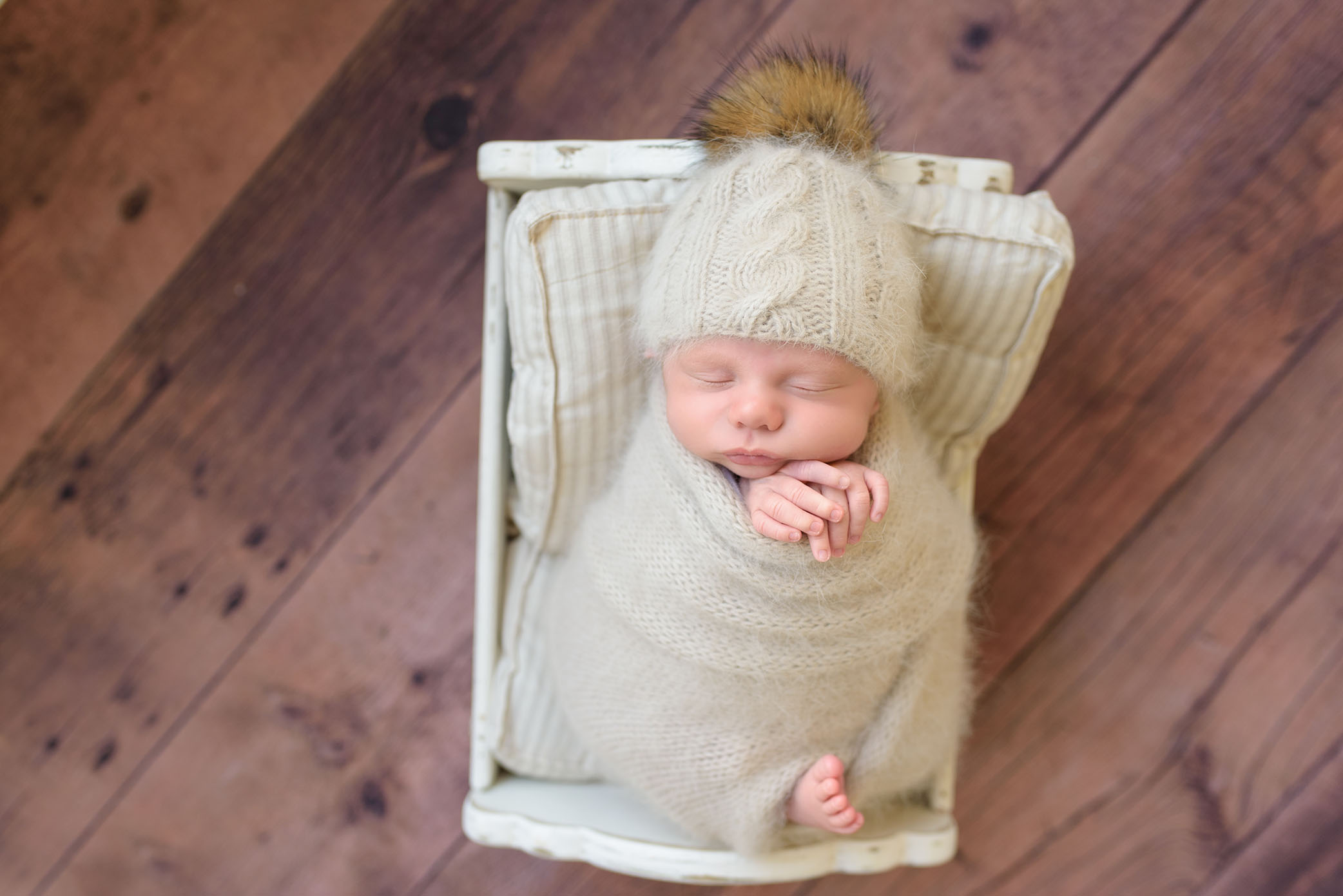 A Newborn Baby Posed On The Floor In Cradle