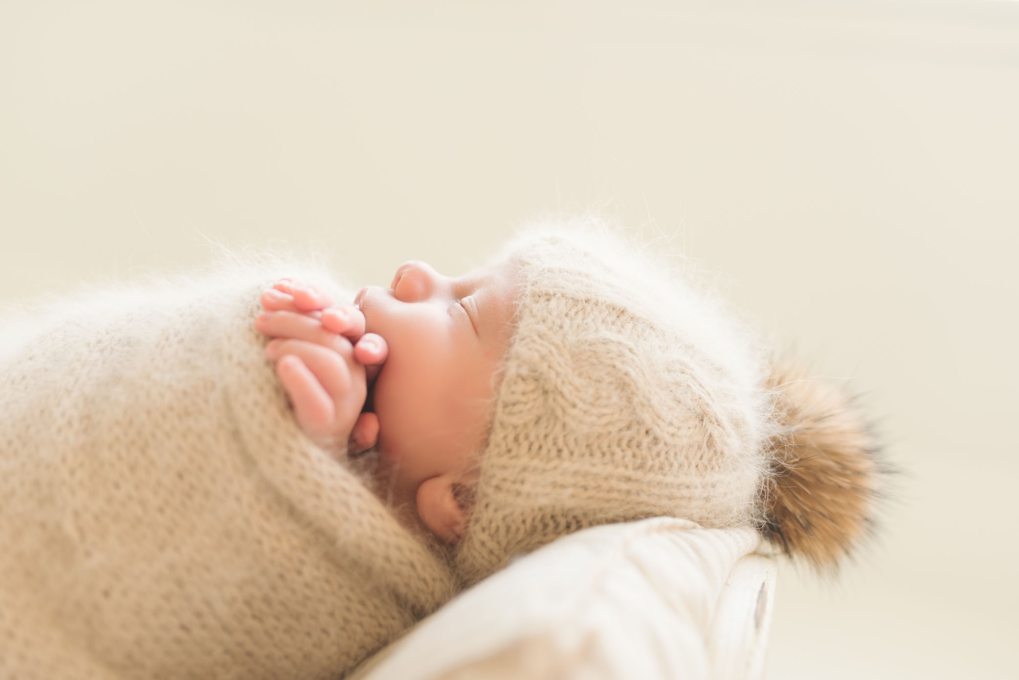 Profile of baby wearing beige fuzzy bonnet captured by Sweet Beginnings Photography by Stephanie