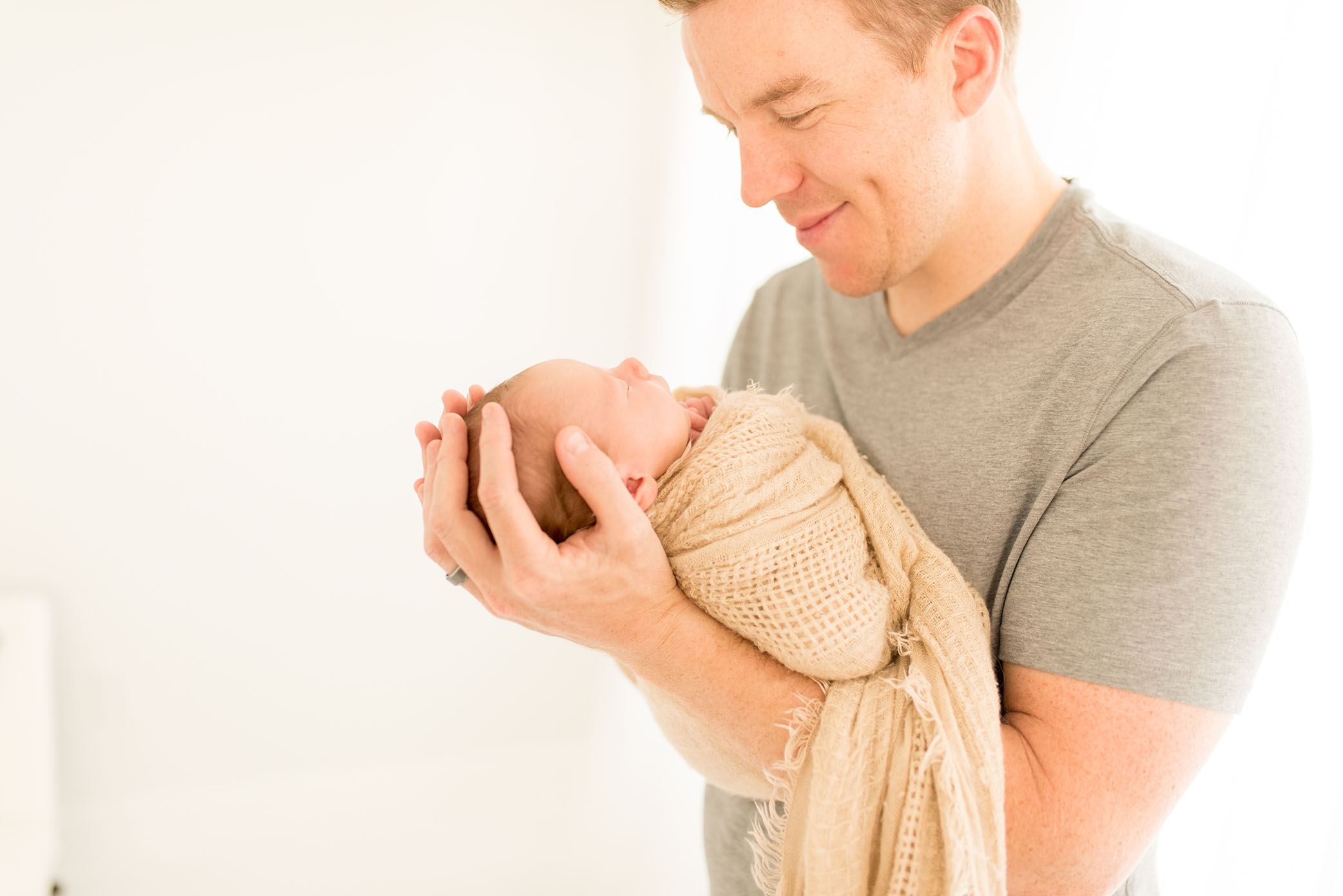 New dad holds his brand new baby in the studio captured by Sweet Beginnings Photography by Stephanie