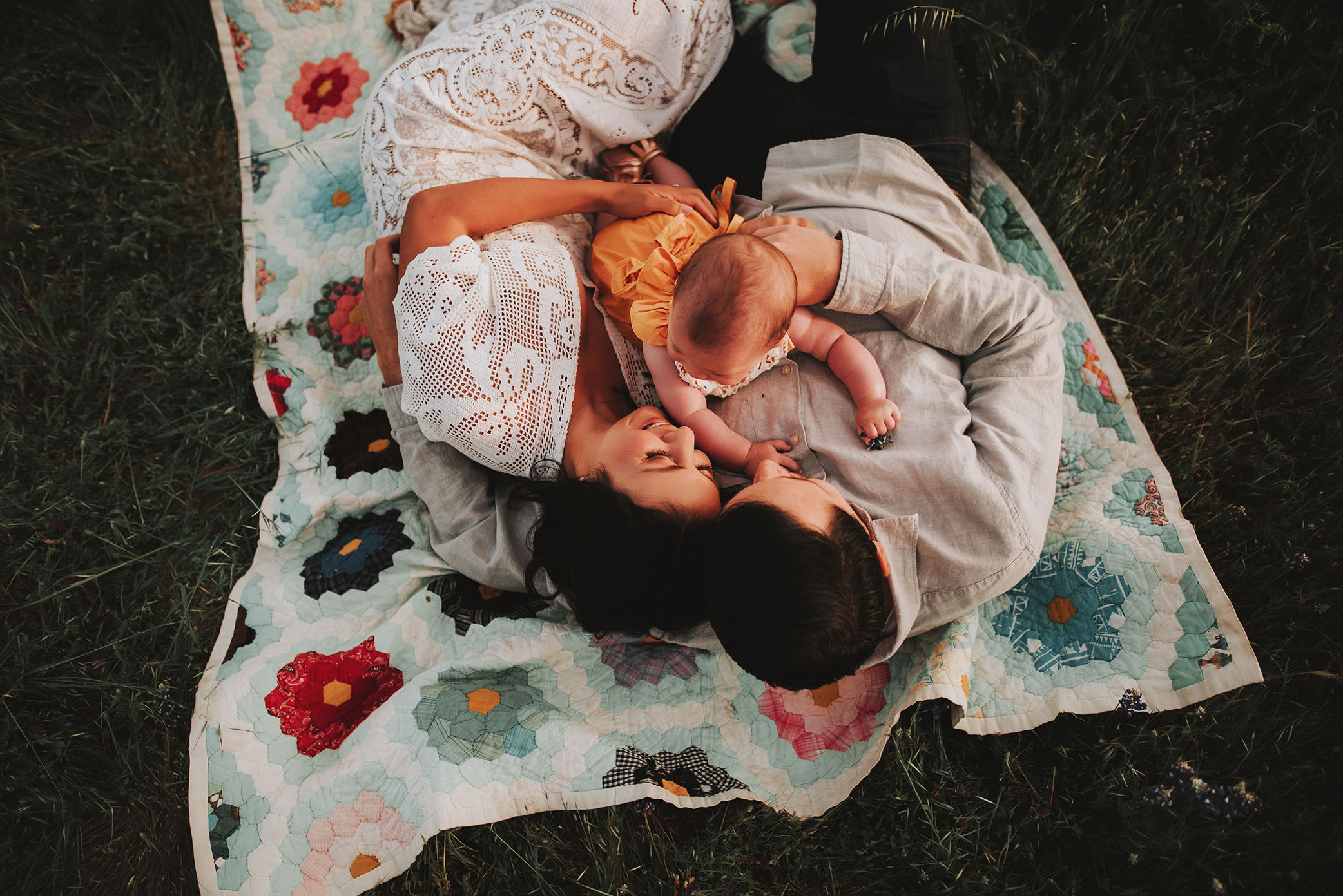 Mother and Father snuggle baby outside on a blanket captured by Sweet Beginnings Photography by Stephanie 