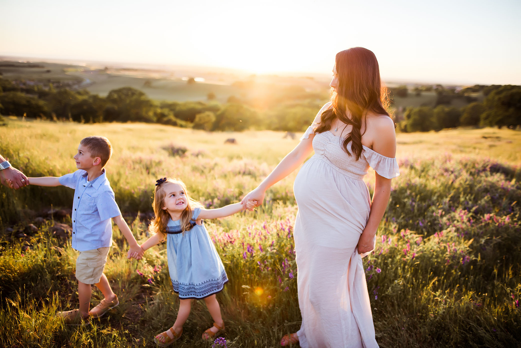 Kids help mom across a grassy hill captured by Sweet Beginnings Photography by Stephanie