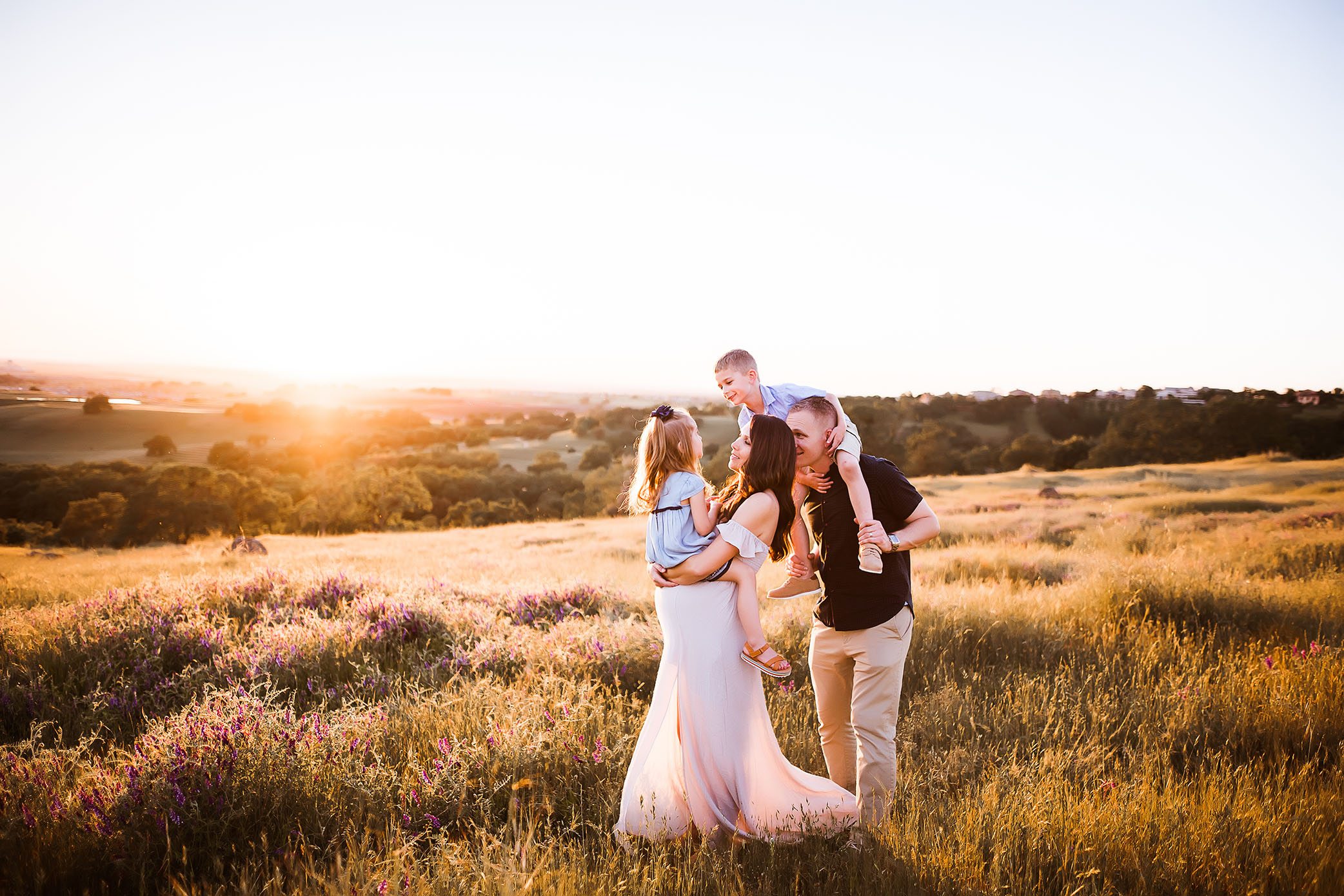 Family posed on a hill in the sunset captured by Sweet Beginnings Photography by Stephanie