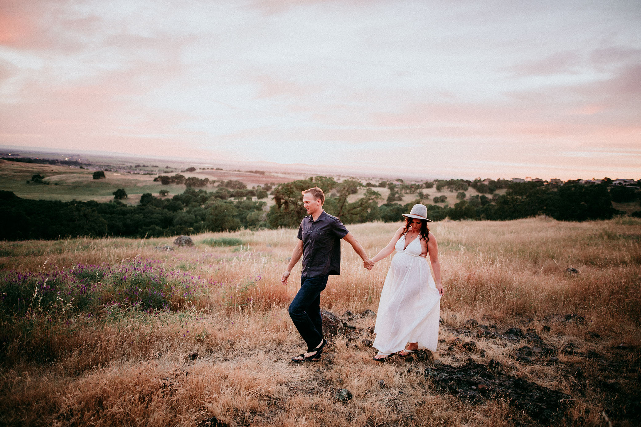 Pregnant mom and dad walk together at sunset captured by Sweet Beginnings Photography by Stephanie