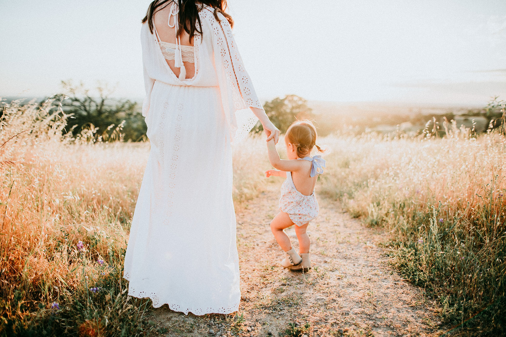 Mom and daughter walk together at sunset captured by Sweet Beginnings Photography by Stephanie