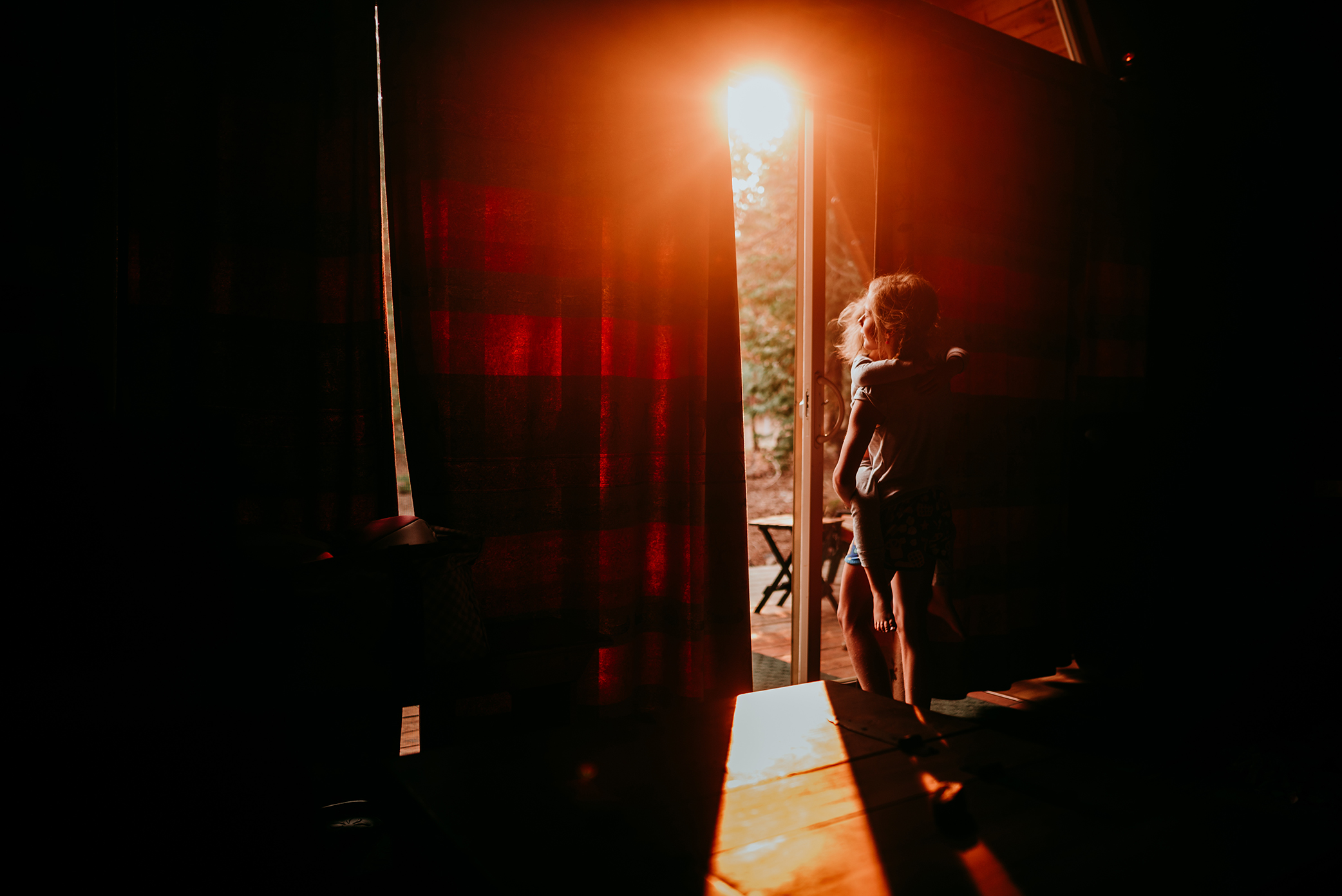 Little girl looking into the morning sun from cabin