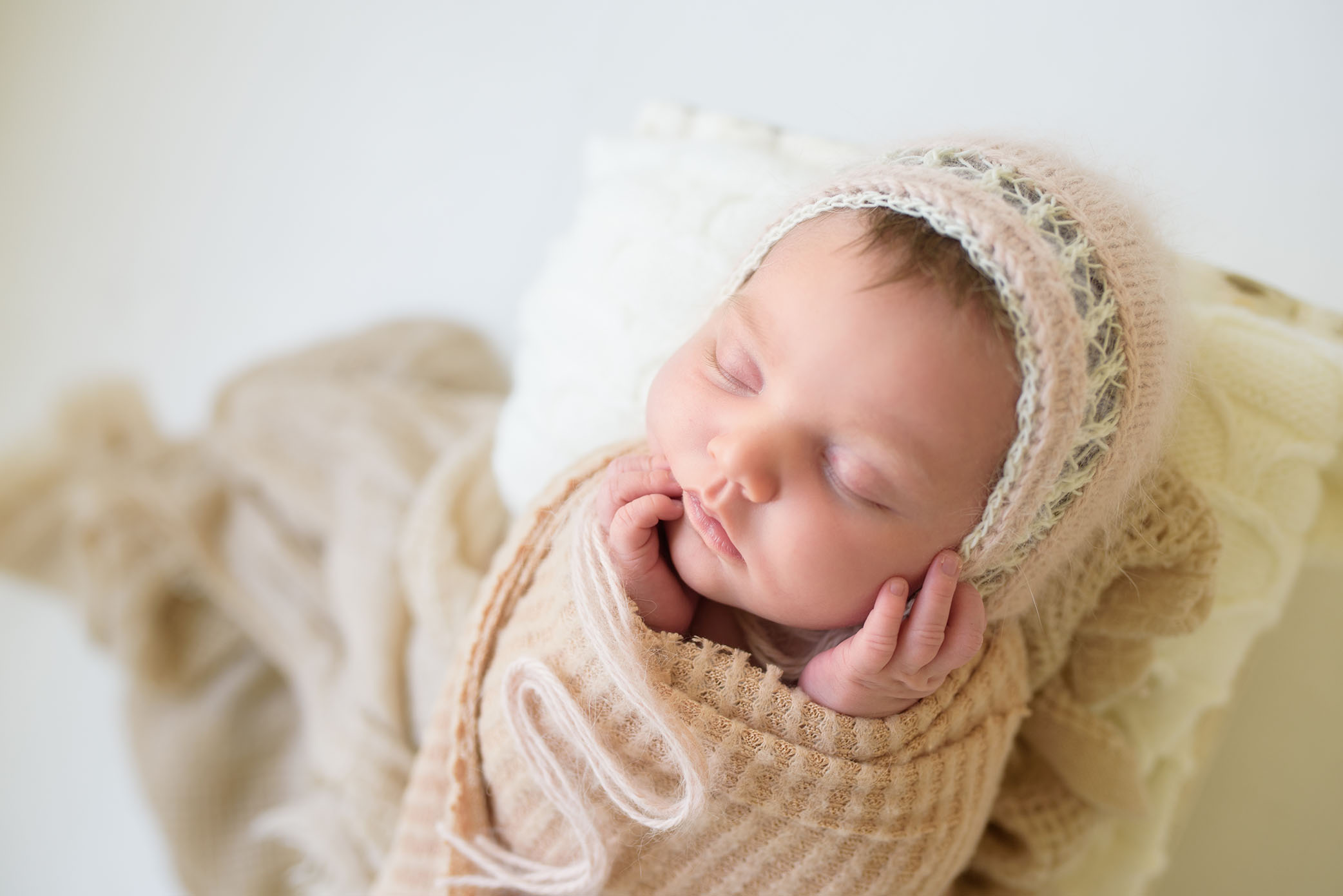 Newborn baby sleeping in the studio dressed in beige