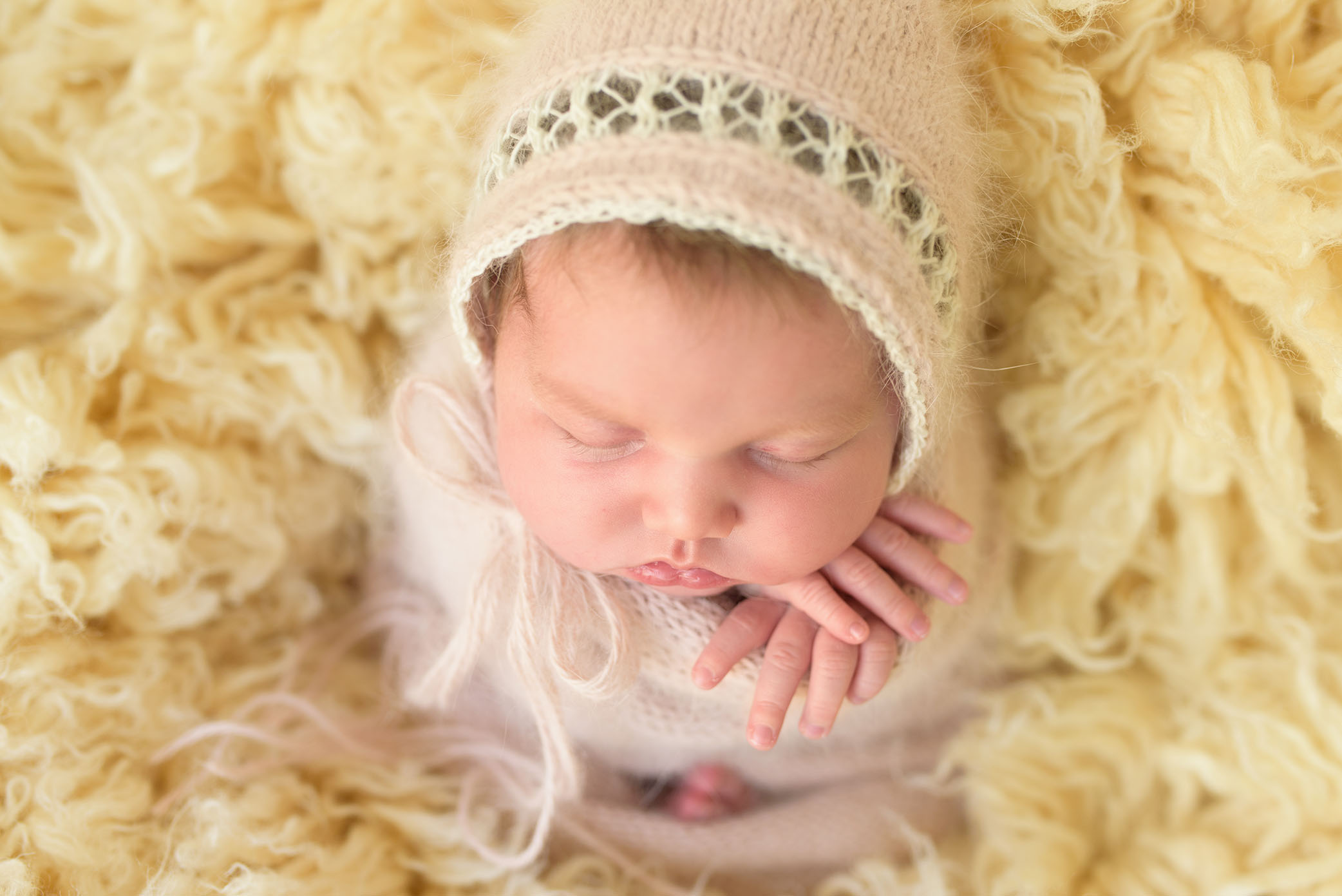 Newborn baby wrapped and posed on flokati