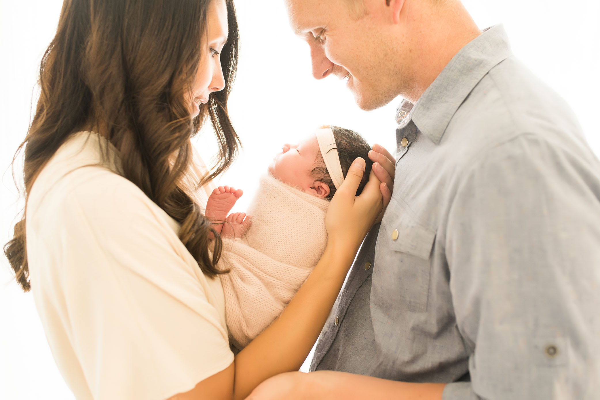 Mom and Dad Look At Newborn Baby Wearing Cream and Grey