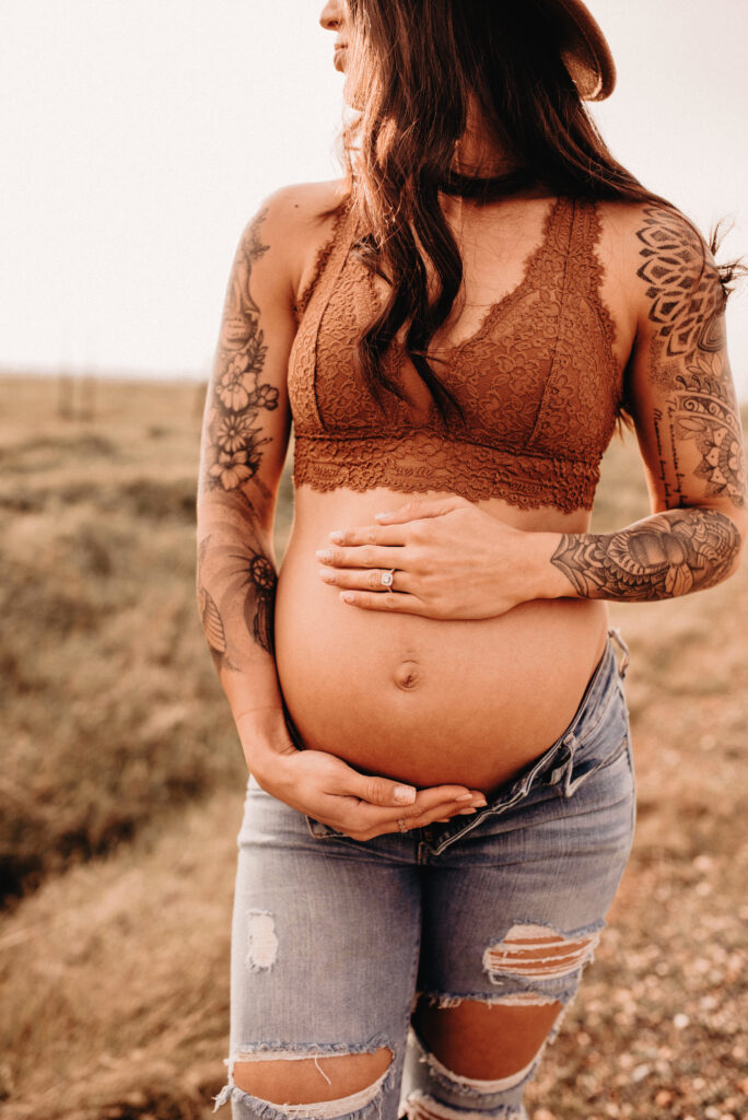 Pregnant mama holding belly with tattoos and arms