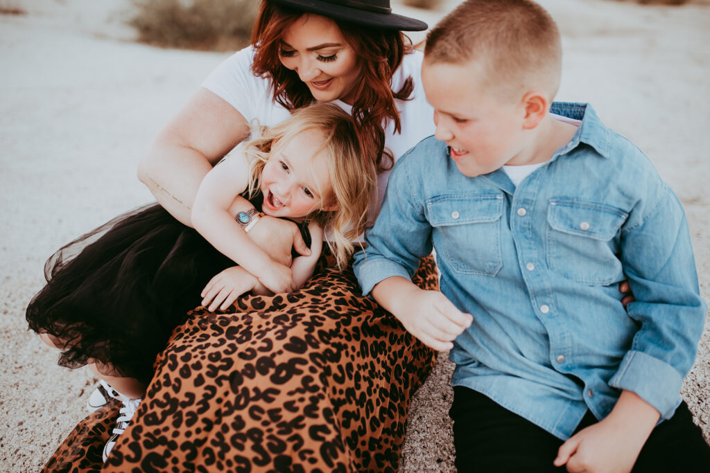 Mom tickles kiddos wearing cheetah print maxi skirt and black hat